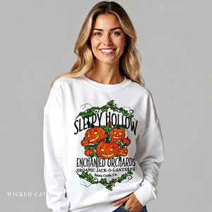 Woman wearing a white sweatshirt with 'Sleepy Hollow Enchanted Orchards' design on a gray background