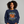 Person wearing a navy blue sweatshirt with 'Sleepy Hollow Enchanted Orchards' design on a gray background