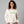 Woman wearing a white sweatshirt with 'ew, people' embroidered on the front.