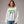 Woman wearing a white sweatshirt with green text that reads Ewww, People. on a gray background