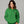 Woman wearing a green hoodie with a Grinch heart design on a gray background