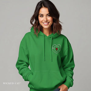 Woman wearing a green hoodie with a Grinch heart design on a gray background