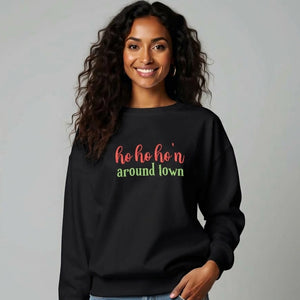 Woman wearing black sweatshirt that reads ho ho ho'n around town in red and green text.