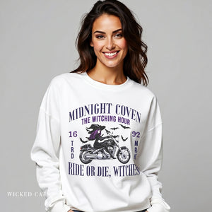 Woman wearing a white sweatshirt with a motorcycle and witch graphic, text 'Midnight Coven' on a gray background.