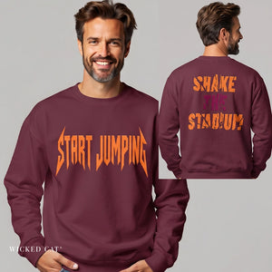 A man modeling a maroon crewneck sweatshirt with orange text reading 'START JUMPING' on the front, shown from the front and back against a light gray studio background. The back also features orange and purple text reading 'SHAKE THE STADIUM'.