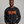 A smiling man wearing a black crewneck sweatshirt with a bold orange graphic text reading 'START JUMPING' across the chest, set against a plain gray studio background.