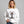 Woman wearing a white sweatshirt with a graphic of a cat tangled in Christmas lights and text the says 'I Regret Nothing'.