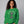woman wearing green sweatshirt with a graphic of a cat tangled in Christmas lights and text the says 'I Regret Nothing'.