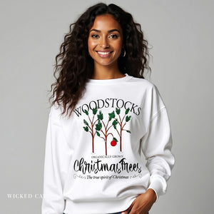 Woman wearing a white sweatshirt with a Christmas tree design and text.