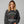 Woman wearing a black sweatshirt with 'Woodstocks Christmas Trees' design on a gray background