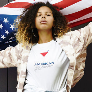 Person wearing a black t-shirt with 'American Woman Patriotic Martini July 4th' design on a plain background