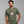 A man wearing an olive green t-shirt with a graphic of a frying pan containing an egg, with the text 'THIS IS NOT AN EGG' printed around it. The brand name 'WICKED CAT' is visible in the bottom-left corner.