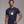 A muscular man wearing a navy blue t-shirt with a graphic of a fried egg inside a frying pan and the text 'THIS IS NOT AN EGG'.