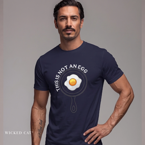 A muscular man wearing a navy blue t-shirt with a graphic of a fried egg inside a frying pan and the text 'THIS IS NOT AN EGG'.