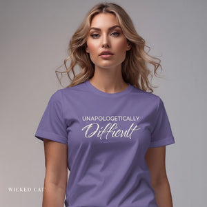 Woman wearing a purple t-shirt with 'UNAPOLOGETICALLY Difficult' text on a gray background