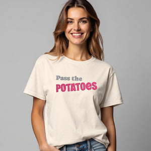 woman wearing an ivory t-shirt with embroidered text that says Pass the Potatoes 