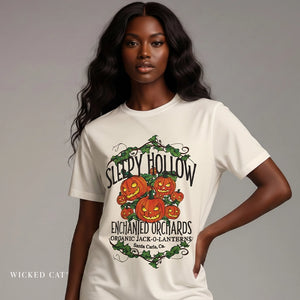Model wearing a white t-shirt with 'Sleepy Hollow Enchanted Orchards' pumpkin design on a gray background