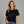 Woman wearing a black t-shirt with 'WAKE UP' text, standing against a gray background.