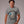 Man wearing grey t-shirt with logo graphic and text 'Eddie's Sewage Service You Dump We Pump Since 1989'.