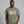 Man wearing a green t-shirt with 'IT NEEDS MORE POWER' text on a gray background