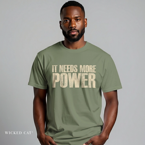 Man wearing a green t-shirt with 'IT NEEDS MORE POWER' text on a gray background