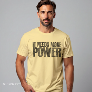 Man wearing a beige t-shirt with 'IT NEEDS MORE POWER' text on a gray background