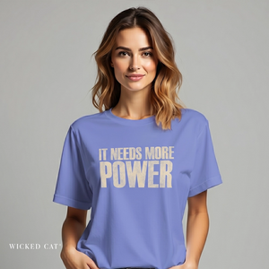 Woman wearing a blue t-shirt with 'IT NEEDS MORE POWER' text on a gray background