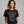 woman wearing a black t-shirt with a graphic of a tangled ball of lights with text It's fine, this is fine, everything is fine.