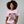 Woman wearing a pink t-shirt with a Christmas-themed graphic and text.