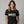 Woman wearing a black t-shirt with 'ELM ST.' printed on it against a gray background