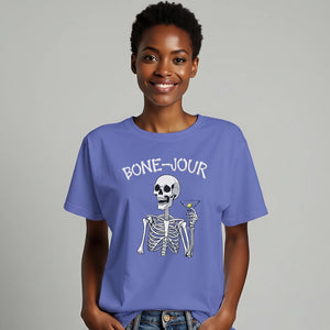 Woman wearing a blue t-shirt with a graphic of a skeleton holding a martini with Bone-Jour in bone style lettering at the top.