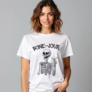 Woman wearing a white t-shirt with a graphic of a skeleton holding a martini with Bone-Jour in bone style lettering at the top.