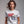Woman wearing a white patriotic t-shirt with a graphic and text King Kings to the Curb since 1776 on a gray background