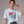 Woman wearing a light blue patriotic t-shirt with a graphic and text Kicking Kings to the Curb since 1776 on a gray background
