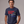 Man wearing a navy blue  patriotic t-shirt with a graphic and text Kicking Kings to the Curb since 1776 on a gray background