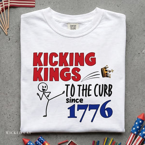 White t-shirt with 'Kicking Kings to the Curb since 1776' text and graphics on a gray surface.