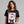 Woman wearing a black t-shirt with a Santa Claus mugshot design on a gray background