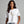 A woman wearing a white short-sleeve crewneck t-shirt with a graphic of a dancing skeleton on the front, paired with blue jeans, against a solid gray studio background. The brand name 'WICKED CAT' is printed in the bottom left corner.