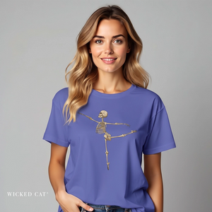 A woman wearing a periwinkle blue t-shirt with a skeleton graphic on the front, posed against a solid gray studio background. The brand name 'WICKED CAT' is printed in white in the bottom-left corner.