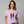 Woman wearing a purple t-shirt with a graphic design and text, standing against a plain background.