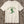 An off-white crewneck short-sleeve crewneck t-shirt featuring a green alien dancing, with the text 'HELLO MY BABY' arched above it, displayed flat on a rustic wood background.