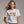 Woman wearing a white t-shirt with 'EXIT LIGHT Enter Night' embroidered text on a plain background