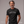 Man wearing a black t-shirt with 'WOOKIN' PA NUB' text, standing against a plain background.
