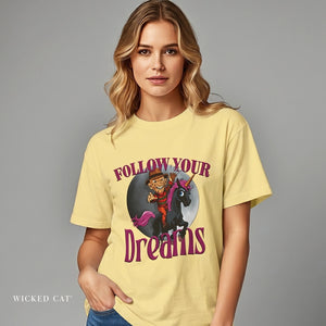 Woman wearing a yellow t-shirt with a graphic design and text 'Follow Your Dreams' on a gray background.