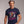 Man wearing a navy blue t-shirt with a graphic design and text 'Follow Your Dreams' on a plain background.