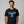 Man wearing a black t-shirt with a blue glass moose mug graphic on a gray background