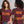 A women's short-sleeve graphic T-shirt shown in front and back views on models. The shirt is dark burgundy with orange gothic-style text reading 'START JUMPING' on the front and 'SHAKE THE STADIUM' on the back, with the middle line in purple.