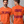 An orange short-sleeve graphic T-shirt shown on a male model from the front and back. The front has the phrase 'START JUMPING' in dark purple gothic-style lettering.