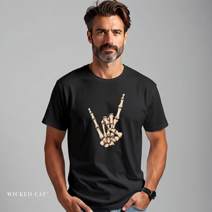 A man wearing a black crewneck t-shirt with a beige skeleton hand graphic making a rock on gesture, set against a plain gray studio background. The brand name 'WICKED CAT' is printed in white in the bottom-left corner.