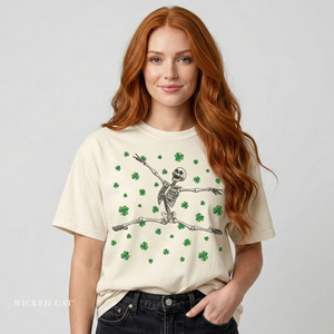 Person wearing a cream t-shirt with a skeleton and shamrock design on a plain background